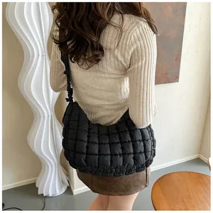 Détail du sac nuage noir matelassé avec bandoulière plissée porté par un mannequin