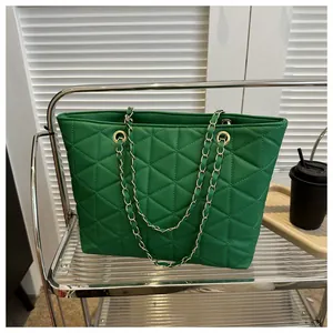 Détail de la texture en cuir matelassé vert et de la bandoulière en chaîne dorée du sac