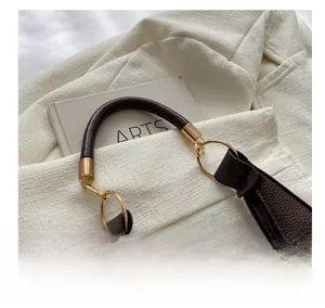 Detail of dark coffee litchi grain leather shoulder bag with gold metal hardware