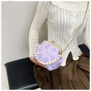 Close-up of purple pleated crossbody bag featuring pearl handle and gold chain detail