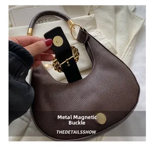 Detail of the high-quality hardware magnetic buckle on a dark brown leather crescent bag