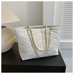 Détail de la texture matelassée et chaîne dorée sur le sac cabas blanc cassé