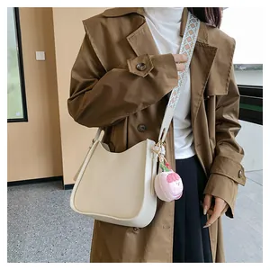 Borsa a tracolla beige a mezzaluna con tracolla geometrica e ciondolo a pesca