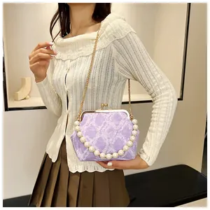 Detail of purple lace fabric bag featuring a pearl handle and vintage metal clasp