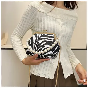 Detail van de crossbodytas met zebraprint, parelhandvat en gouden metalen ketting