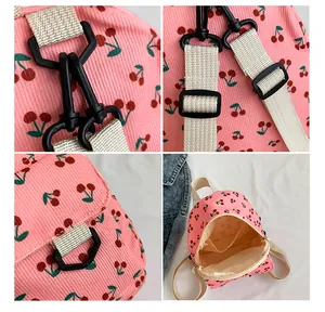 Detail of pink corduroy mini backpack with cherry print, showing straps and plastic buckles