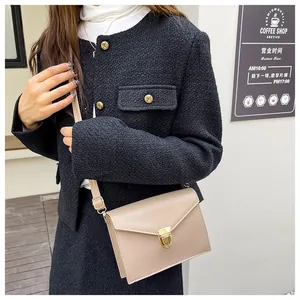 Detailansicht einer beige Umhängetasche aus Kunstleder mit goldenem Drehverschluss am Model