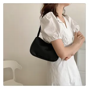 Detailaufnahme der schwarzen minimalistischen Achseltasche aus Leder am Model in Weiß