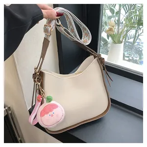 Dettaglio borsa hobo crema con tracolla a motivi e ciondolo a forma di pesca rosa