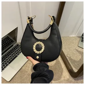 Detail of black pebbled hobo bag with large golden textured metal ring buckle