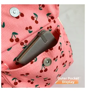 Detail of pink corduroy cherry bag featuring a practical outer pocket with metal magnetic snap