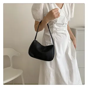Schicke schwarze Unterarmtasche mit Litschi-Muster als Lifestyle-Accessoire am Modell