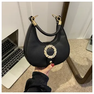 Detail of black pebbled leather half-moon bag with decorative gold metal hardware