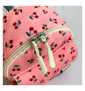 Detail of pink corduroy mini backpack featuring cherry print and smooth double zippers