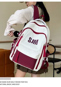 Detalle de la mochila multibolsillos con logo SJM y pompón decorativo de peluche negro