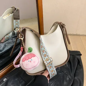 Borsa a tracolla retrò crema con bordo marrone, tracolla intrecciata e ciondolo pesca