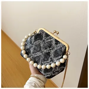 Detail van grijze denim tas met parelhandvat, kettingriem en gewatteerde franjes