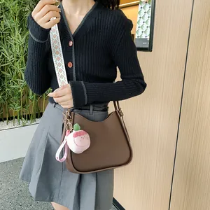 Borsa a secchiello marrone scuro con tracolla intrecciata e ciondolo a fragola