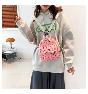 Close-up of pink corduroy mini backpack with cherry print and white woven straps