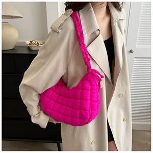 Sac fourre-tout matelassé rose vif avec bandoulière froncée sur un trench beige