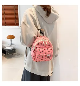 Detailed view of pink corduroy mini backpack featuring red cherry prints and adjustable straps