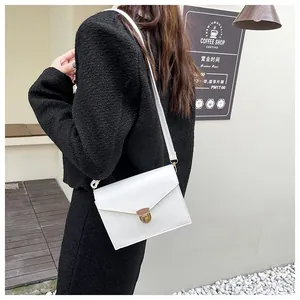 Nahaufnahme der weißen Leder-Umschlagtasche mit goldenem V-Metallverschluss und Gurt