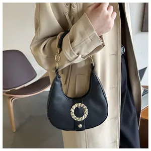 Detail of black leather crescent bag with golden twist buckle and round rigid handle