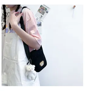 Detail of black corduroy mini crossbody bag with cute bear patch and plush charm
