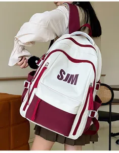 Detalle de la mochila de gran capacidad crema y rojo oscuro con logo SJM y bola de felpa