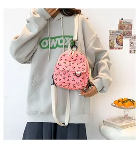 Detailed view of pink corduroy mini backpack with red cherry pattern and adjustable strap