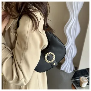 Detail view of a black pebbled leather half-moon bag with a gold round buckle clasp