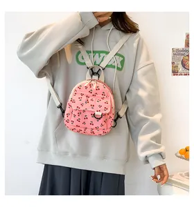 Detailed shot of pink corduroy mini backpack with cherry prints and black D-ring decor