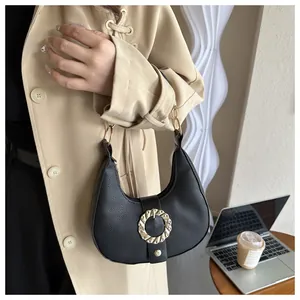 Detail of black crescent shoulder bag with large golden textured metal buckle on lychee leather