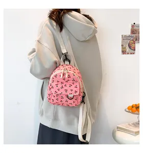 Detail of pink corduroy mini backpack with cherry print on model with white strap