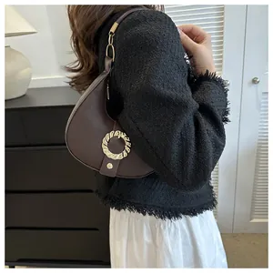 Detail of coffee crescent hobo bag with gold ring buckle and lychee leather texture