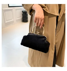 Detailed shot of a black faux fur handbag featuring a gold kiss-lock and metal chain