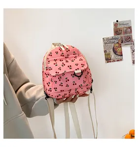 Close-up of pink corduroy mini backpack with cherry print and webbing shoulder straps