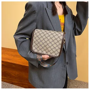 Détail d'un sac bandoulière vintage avec texture géométrique et large sangle florale