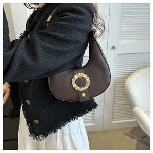 Detail of dark brown lychee leather hobo bag with a wavy gold metal buckle and strap