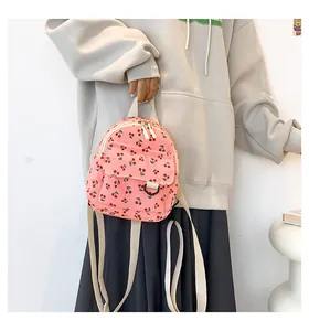 Detail of pink corduroy mini backpack with cherry print and white adjustable straps