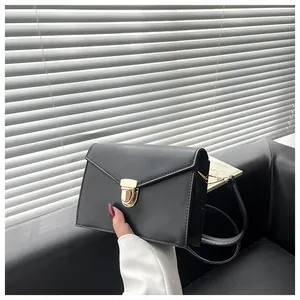 Detail einer minimalistischen schwarzen Briefumschlag-Tasche mit goldenem Verschluss