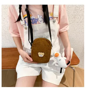 Close-up of brown corduroy crossbody bag with bear embroidery and white duck plush charm