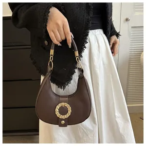 Detail of dark brown hobo bag with gold ring buckle and textured lychee leather