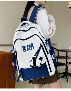 Detalle de la mochila escolar azul y blanca con logo SJM y llavero de peluche de panda