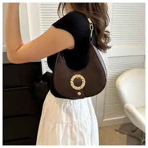 Detail of dark brown lychee textured half-moon bag with elegant golden metal buckle