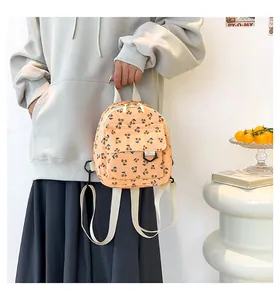 Detail of orange corduroy mini backpack featuring cherry patterns and a front flap pocket