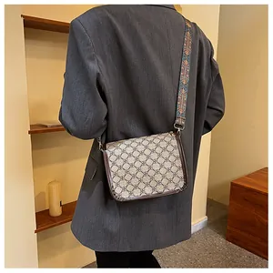 Détail du sac bandoulière vintage avec sangle à motifs porté sur un blazer gris