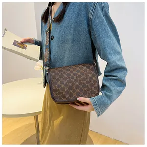 Vue détaillée du sac bandoulière marron vintage avec motif floral et large sangle tissée