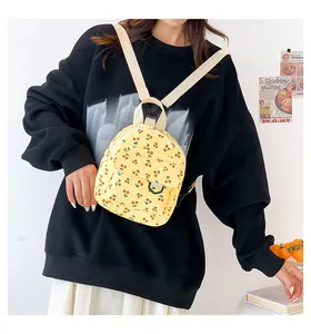 Close-up of yellow corduroy backpack with cherry pattern on a model in casual setting