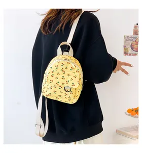 Detail of yellow corduroy mini backpack featuring cherry prints and fabric straps